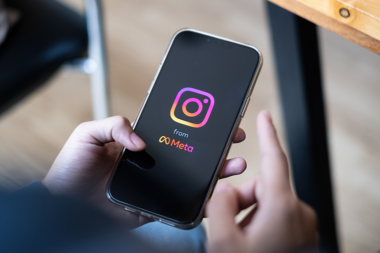 Image of a person holding a smart phone that has the Instagram logo on the front