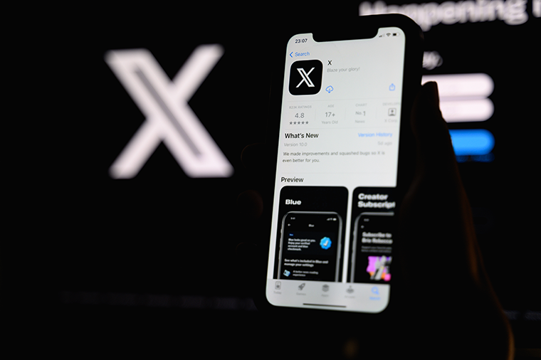 Image of X app in the app store on an iPhone with X logo in the background on a black surface